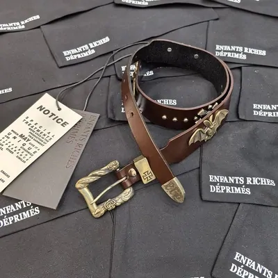 Coiled brown leather belt with silver studs and a western buckle