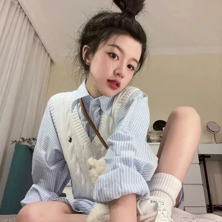 Model in an oversized white striped shirt and white socks, seated