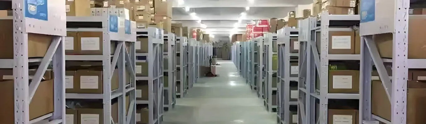 Warehouse aisle with tall shelving racks packed with labelled parcels and storage bins on both sides